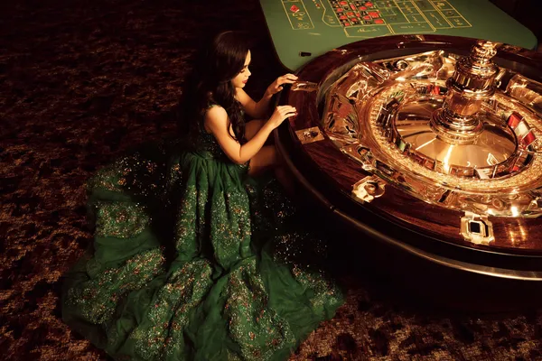Một người phụ nữ quyến rũ cầm chip casino trong không gian ánh đèn rực rỡ, đại diện cho bầu không khí casino trực tuyến của KHOIDNS.