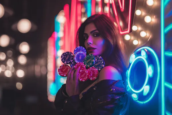 Một cô gái trong bộ váy xanh sang trọng đứng cạnh vòng roulette, gợi lên bầu không khí casino cao cấp của KHOIDNS.